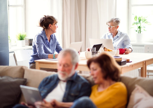 Group of senior people using laptops and tablets in community center club.