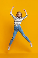 Fototapeta na wymiar Carefree girl jumping with her hands up