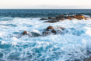 ocean waves cover a stone coast