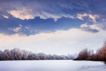 Winter landscape with snowy trees and heavy dark clouds_