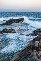 waves of the ocean are breaking from the rocky coast (vertical photo)