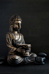 Bronze Gautama Buddha with Dark Rocks Isolated on Black