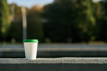 Coffee to go. A plastic glass stands on the promenade. 