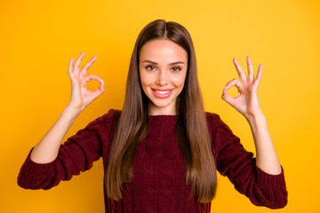 Close up photo of lovely lady showing ok signs smiling wearing maroon jumper isolated over yellow background