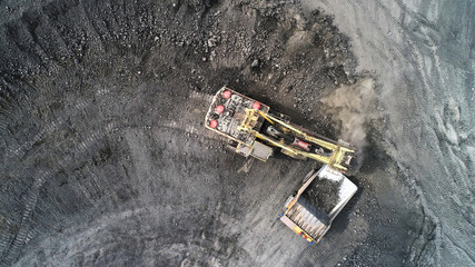 Cable excavator loads overburden from the body of a mining truck.