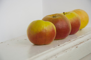Raw red and green apples on white wooden table
