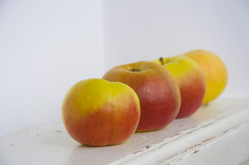 Raw red and green apples on white wooden table