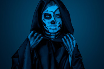 Female death in hooded cloak under blue light