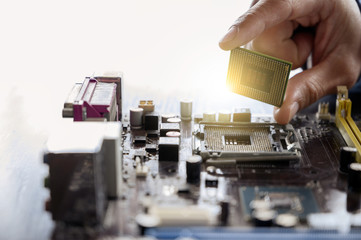 The asian technician is putting the CPU on the socket of the computer motherboard. the concept of...