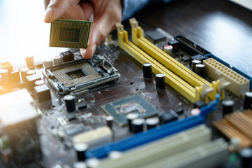 The asian technician is putting the CPU on the socket of the computer motherboard. the concept of...
