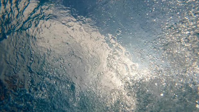 Slow motion of bubbles underwater with sunshing through water surface