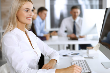 Business woman using computer at workplace in modern office. Secretary or female lawyer smiling and looks happy. Working for pleasure and success