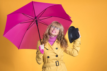 adult woman with umbrella and autumnal clothes isolated on color background