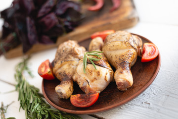 fragrant and delicious chicken drumsticks lie on a plate, a wooden table, a piece of rosemary gives a pleasant aroma.
