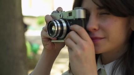 Tilt up portrait shot slow motion of smiling caucasian young woman making a photo holding a camera in park 