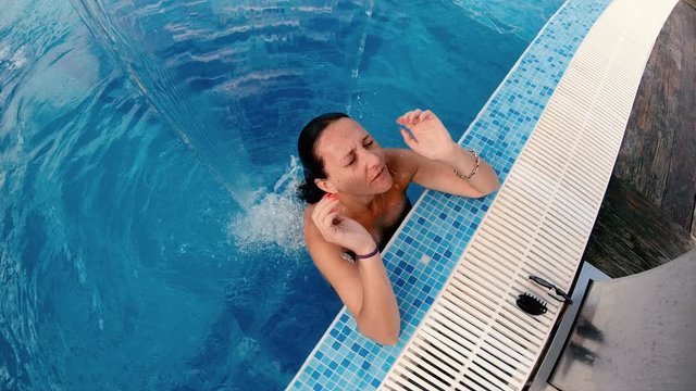 Slow motion of a beautiful woman in a luxury pool under water jat enjoying