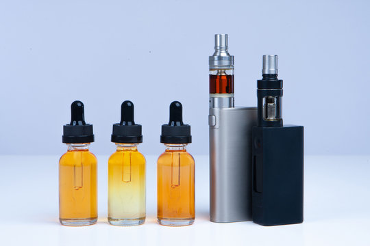Juice for vape. Vaping. Devices for the vaper and three bytes of liquid. Oils for vaping on the table. Sale of vaping liquids. Juice for e-cig. Vaper table. Refueling a vape device. Vape kit