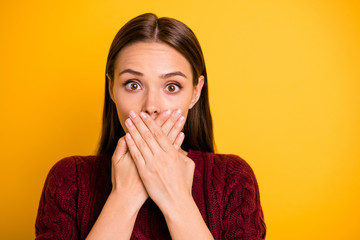 Close up photo of girl with her mouth covered with hands while isolated with yellow background keeping silence