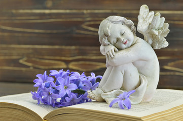 Guardian angel and blue hyacinth flower on old book