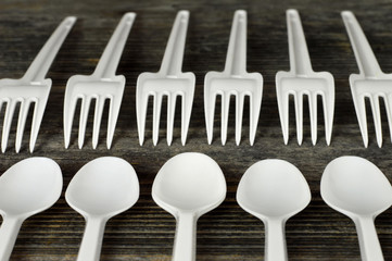 Plastic cutlery on wooden background. Disposable plastic forks and spoons