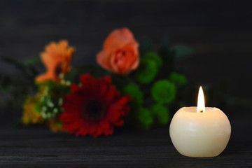 Obraz na płótnie Canvas Condolence card with burning candle and flowers on dark background
