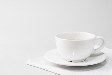 white cup with tea on a saucer on a napkin on a light background. copy space for text