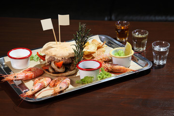 Burger and langoustines with sauce on a tray.