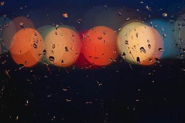 Light of lanterns in blurry background with raindrops on glass