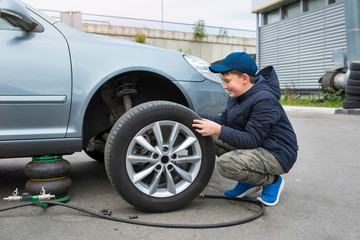  Apprentice auto mechanic changes the wheel of a car.  Auto repair concept.