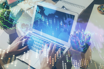 Double exposure of man's hands writing notes with laptop of stock market with forex graph background. Top View. Concept of research and trading.