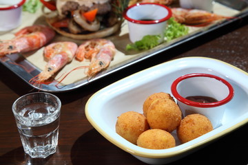 Fried balls of cheese. Cheese balls fried in breadcrumbs with sauce. Deep Fried Breaded Cheese. Burger and langoustines with sauce on a tray.