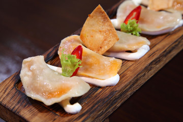 Dumplings with potato in sour cream on a wooden board.  Dumplings with mushrooms. Dumplings with cherries.