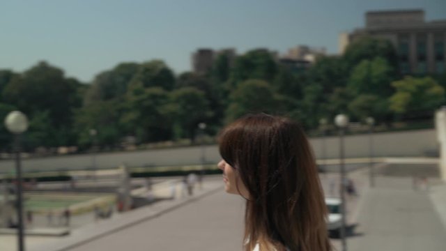 Circular middle pan shot of elegant woman dressed in white shirt and black skirt making photo of Eiffel Tower with film camera