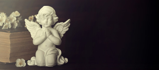 Sympathy card. Guardian angel, spring flowers and old book on dark background with copy space