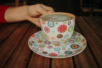 hands holding cup of coffee on wood background