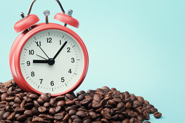 Red alarm clock standing in heap of coffee beans. Сoncept of morning awakening, beginning of working day