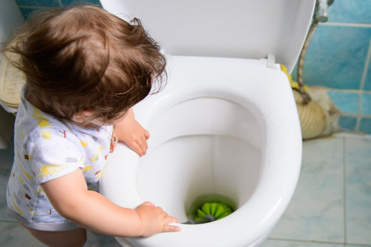 the child cleans the toilet. Child labour. Little girl cleans the toilet. toilet brush. grooming yourself. training a child for cleaning.