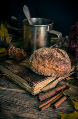 Steel cup of tea and a bun on a seasonal rustic background, close up still life
