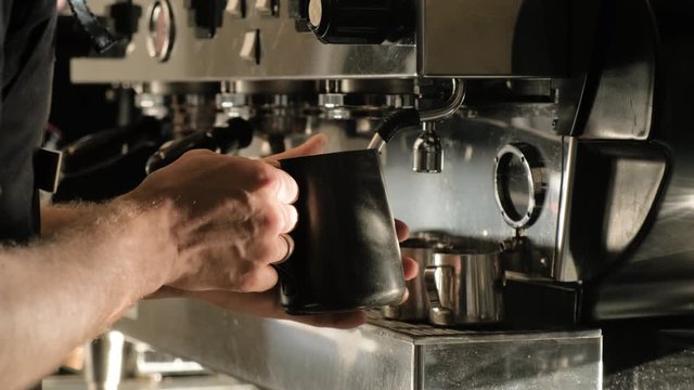 Close up of barista hands steaming milk for a latte or cappuccino