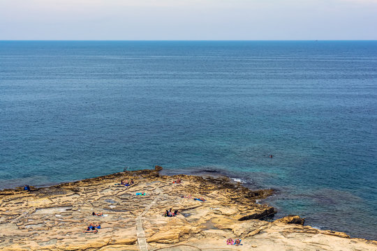 People relaxing on the Silema beach in Malta getting tanned and swimming in Mediterranean Sea.