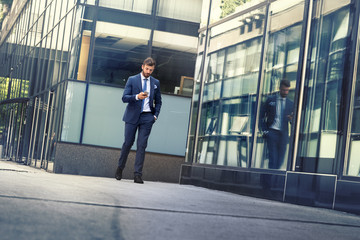 Businessman walking at street looking at smartphone