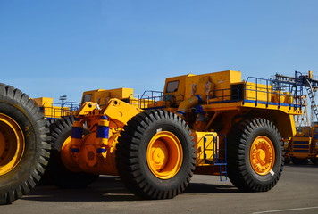 Heavy-duty trucks warehouse at autoworks. Giant mining dump trucks manufacture by the heavy vehicle plant. Heavy quarry equipment. Coal mining, granite, gravel, sand.