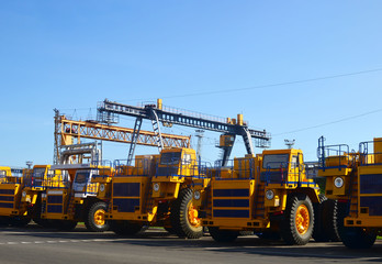 Fototapeta premium Heavy-duty trucks warehouse at autoworks. Giant mining dump trucks manufacture by the heavy vehicle plant. Heavy quarry equipment. Coal mining, granite, gravel, sand.