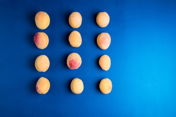 Many  apricots on a blue background. Flat lay composition with hard light