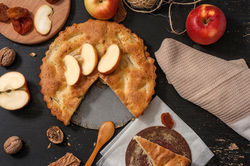 Apple Pie Charlotte on a black wooden table with red apples in iron form.Top view.