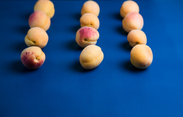 Many  apricots on a blue background. Flat lay composition with hard light