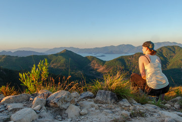Naklejka premium A young travel woman from backside sitting on the top of Angel Mountain in Nha Trang, Vietnam 