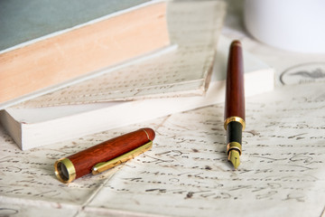 fountain pen on old blank papers in front of books
