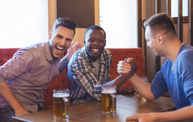 Arm Wrestling. Male Friends Having Fun In Bar
