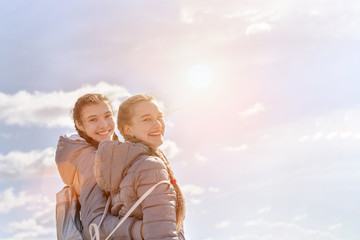 Two female friends having fun outdoor blue sky with clouds background